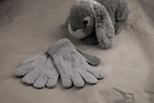 Gray Desky Gloves On The Background Of Kraft Paper With A Plush Hare