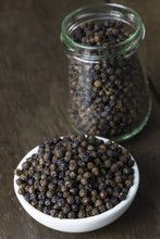 Pile Black Pepper On White Bowl And Glass Jar On Old Wooden Table.