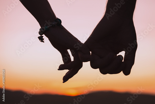 Cuadros en Lienzo Silhouettes of female and male hands holding hands against background of setting sun