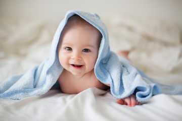 Wall Mural - Cute little baby boy, relaxing in bed after bath, smiling happily