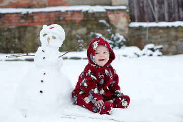 Wall Mural - Little cute smiling baby boy, sitting outdoors in the snow