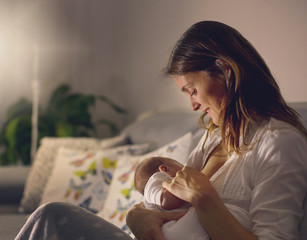 Poster - Young beautiful mother, breastfeeding her newborn baby boy at night