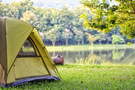 Camping green tent in forest near lake