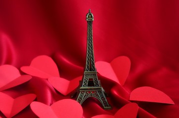 The Eiffel Tower and red hearts in a silk background.