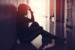Silhouette of sad and depressed women sitting at walkway of condominium or office with backlit and lens flare,sad mood,feel tired, lonely and unhappy.