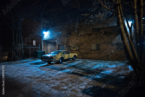 Fotografie, Obraz Vintage muscle car in a dark Chicago city urban alley on a winter night