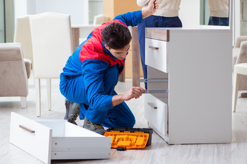 Wall Mural - Contractor repairman assembling furniture under woman supervisio