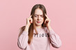 © sementsova321 - Brunette female model tries to recollect something in her mind, keeps fingers on temples, has forgetful expression, keeps eyes shut, focused on remembering information, isolated over pink wall
