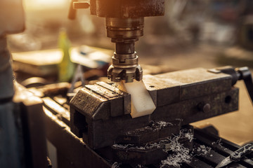 Close up view of machine grinding plastic part on vise tool in the industrial workshop.