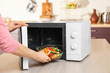© Africa Studio - Woman putting bowl with vegetables in microwave oven, closeup