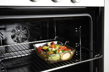 Wall Mural - Glass baking dish with vegetables in oven