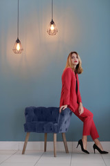 Wall Mural - Beautiful young stylish woman and armchair near color wall