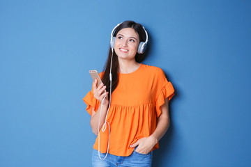 Wall Mural - Woman listening to audiobook through headphones on color background