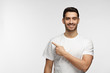 © Damir Khabirov - Handsome man in white t-shirt pointing left with finger isolated on gray background