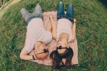 Couple Of Young Lovers In Sunglasses Are Lying On The Grass And Smiling, Top View