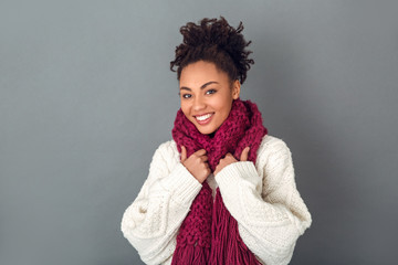 Wall Mural - Young african woman isolated on grey wall studio winter concept wearing scarf