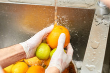 Chef Washing Citrus Fruits In A Sink. Tap Water Flowing On A Orange And Splashing Around. Splashing Water.