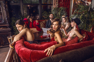 Group of young stylish people dressed classical style in interior of luxury club.