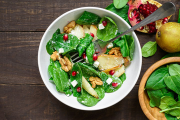 Wall Mural - salad with spinach leaves, pear, nuts, pomegranate and feta cheese in a bowl with fork
