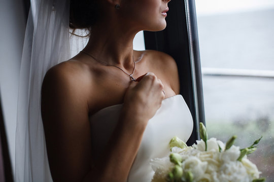 Girl in a white dress with a beautiful silver chain around her neck
The bride fixes a decoration of a jewel on the neck
Stylish fashionable diamond suspension
the bride fixes the cross on the neck