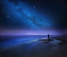 starry night sky over sea and beach with man silhouette