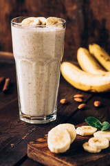 Wall Mural - Banana smoothie in glass on brown wooden table. Healthy food, healthy eating concept