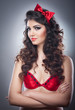 © iancucristi - Attractive girl with a red bow on her head and red bra send a kiss.Pinup model on grey background.Beautiful pinup model head shot with red bra and smiling