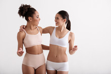 Happy Athletic Friends Hugging Each Other And Smiling. Girls Are Wearing Tight Underwear. Isolated On Background