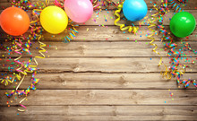 Colorful Carnival Or Party Frame Of Balloons, Streamers And Confetti On Rustic Wooden Board