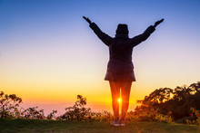 Silhouette Of Woman Arms Up Outstretched For Praying With Sunbeam On Hill. Christian Praise On Hill At Sunset.