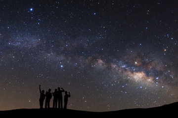 Wall Mural - landscape with milky way, night sky with stars and silhouette of a standing sporty man with raised u