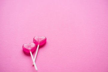 Couple of 2 heart shaped lollipops on pink. Valentine's day background, greeting card concept.