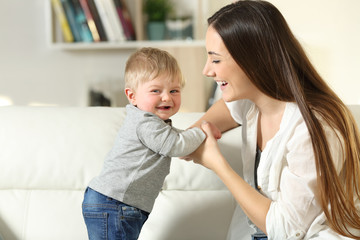 Canvas Print - Mother helping to stand to her son who looks at you