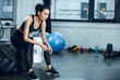 © LIGHTFIELD STUDIOS - young fit woman sitting on workout wheel after training at gym