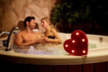 heart on a background of a romantic couple with champagne in the jacuzzi. valentines day.