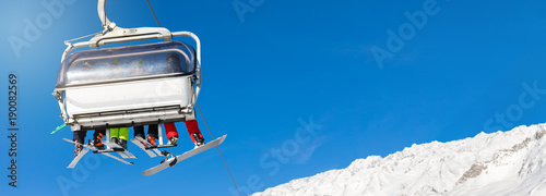 Fotografía skiers and snowboarders in a ski lift against clear blue sky