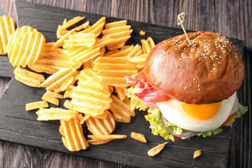 Wall Mural - Wooden board with tasty burger and chips on table