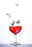 Fototapeta Paryż - Eiswürfel fallen  in ein Glas mit rotem Getränk