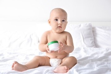 Wall Mural - Cute baby with jar of body cream on bed