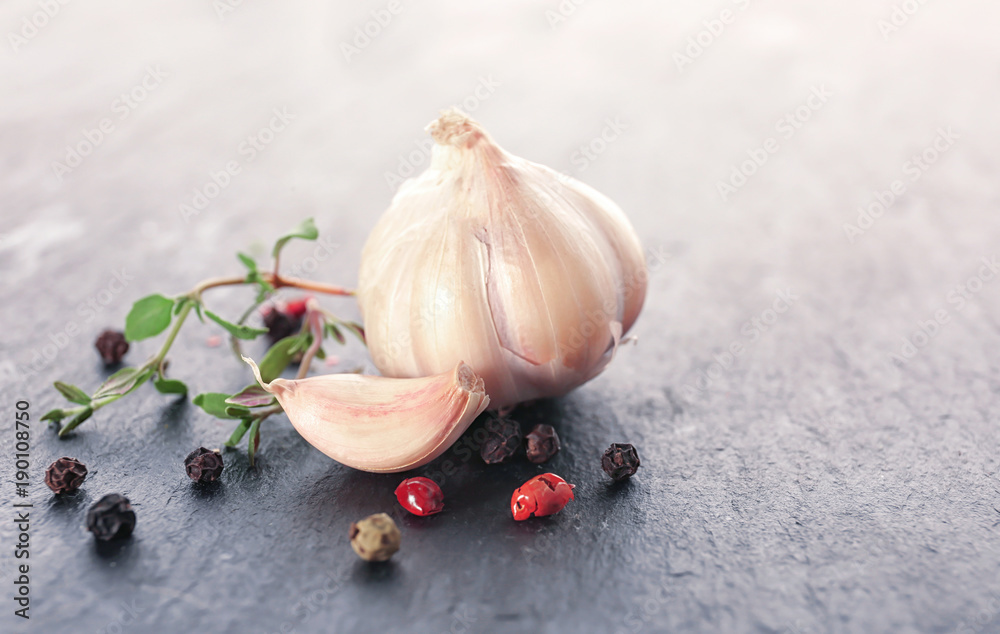 Fresh garlic and pepper grains on grey background