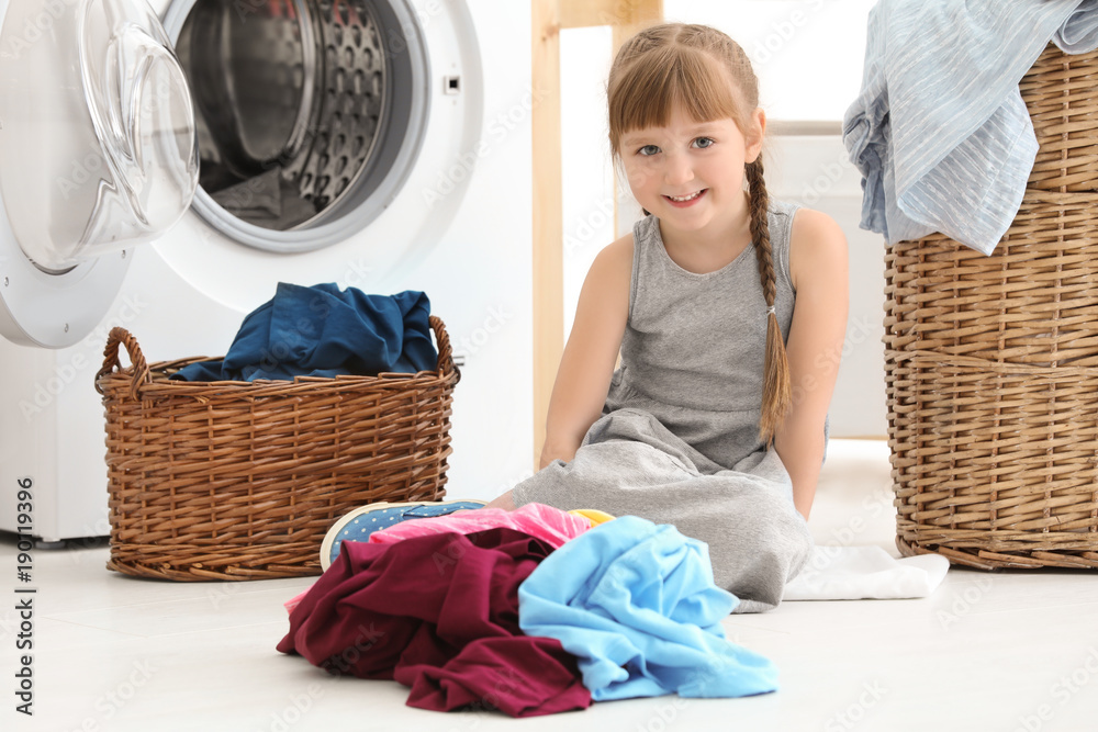 Cute little girl doing laundry indoors