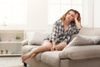 © Prostock-studio - Young woman sitting on beige couch