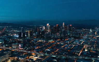 Wall Mural - Aerial view of Downtown Los Angeles at twilight with young woman holding out a smartphone in her hand