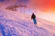 Skier in ski resort. Red sunset sky in background.