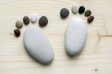 Two Tiny Stone Feet And Ten Toes On Wooden Background, Stone In The Shape Of A Human Feet
