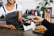 © Artem Varnitsin - Customer making wireless payment using smartphone in cafe
