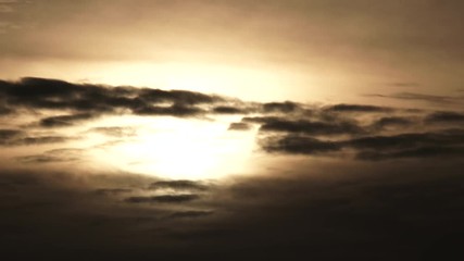 Wall Mural - Time lapse as glowing sun drops behind dark clouds at sunset, day to night.