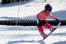Little Cute Girl Snowboarding  Making A Tricks At Ski Resort In Sunny Winter Day. Caucasus Mountains. Mount Hood Meadows Oregon 