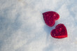 © virginna - St Valentine's day card. Two red hearts laying on white snow. Top view, space for text
