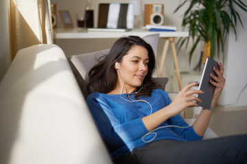     Woman sitting on sofa and using tablet. 